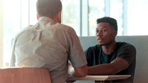 two men sitting on a table talking