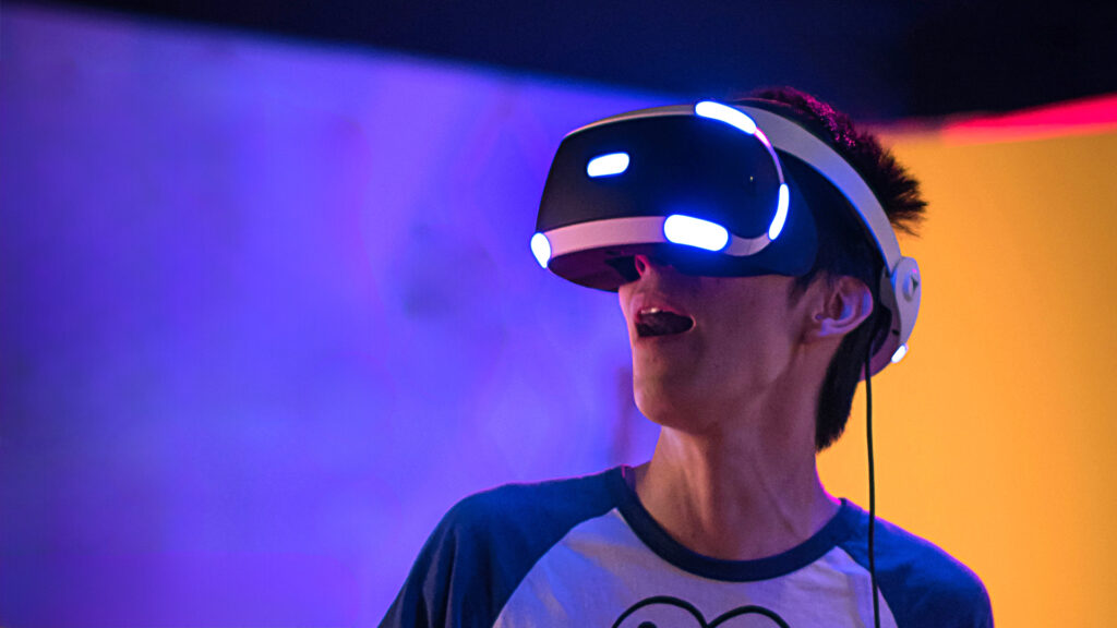 Jugendlicher mit VR-Brille vor buntem Hintergrund.